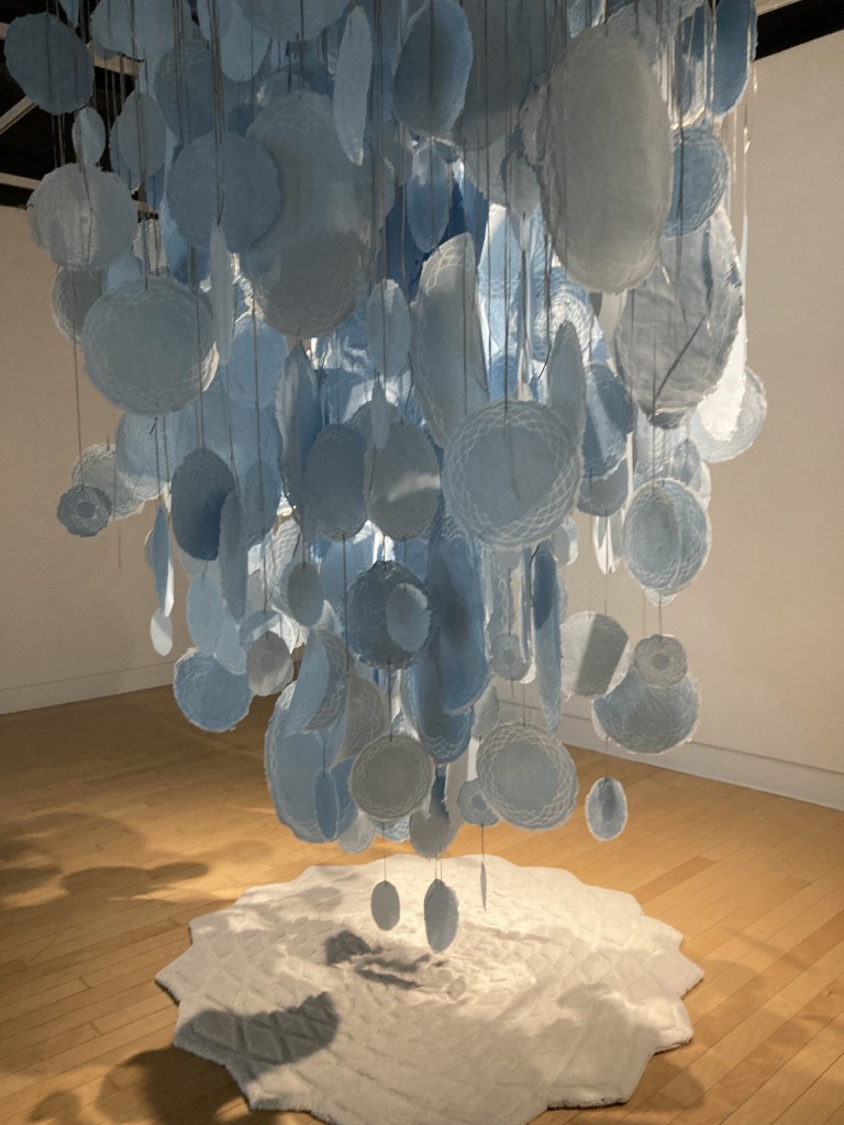 11)“of fog”, 500+ shaped & watermarked handmade paper sheets from indigo dyed linen & cottons, ribbon, indigo dyed fabric, safety pins, & rug tufting, 11’t x 6’ x 6’, 2023